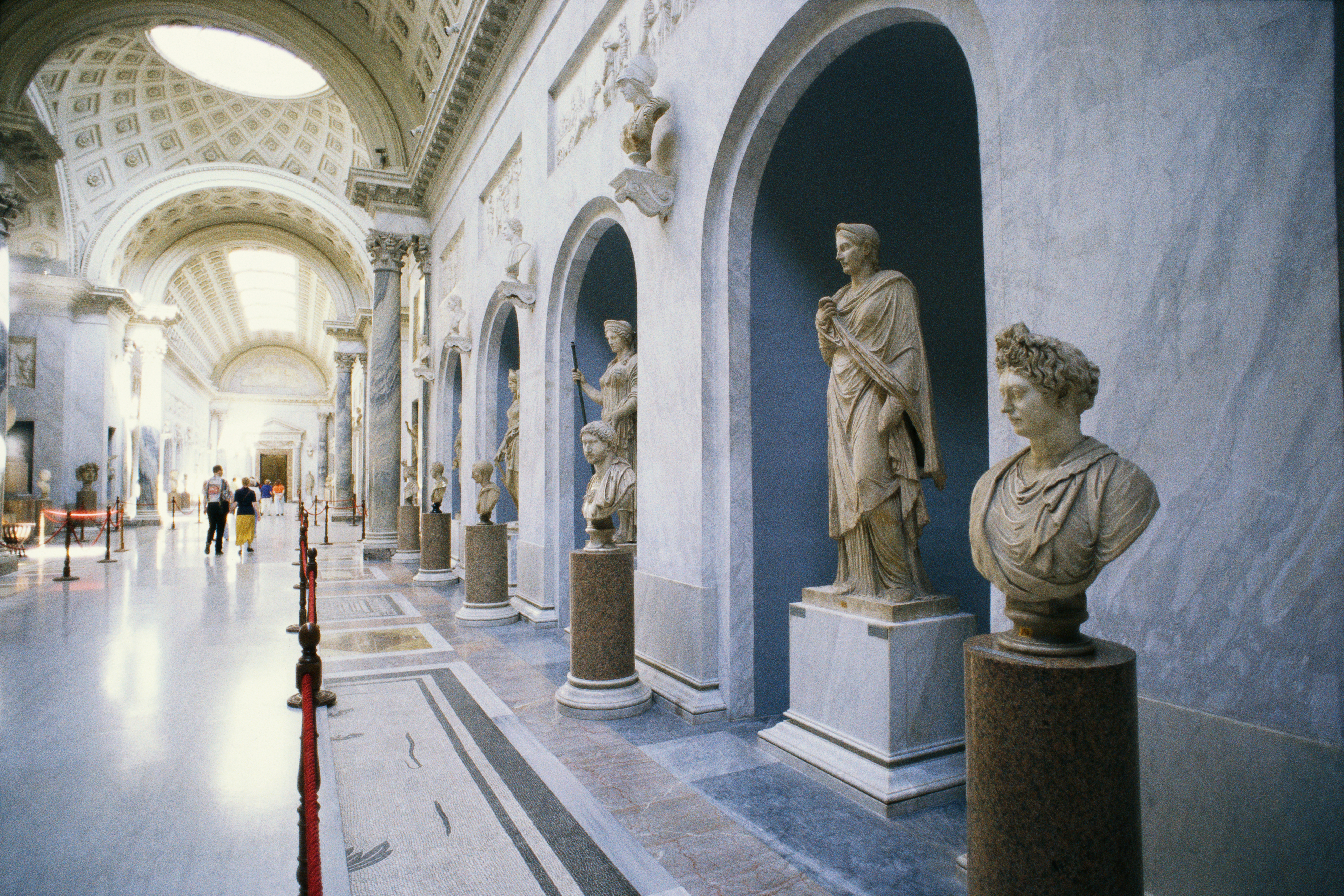 The interior of a gallery in the Vatican museums lined with sculptures