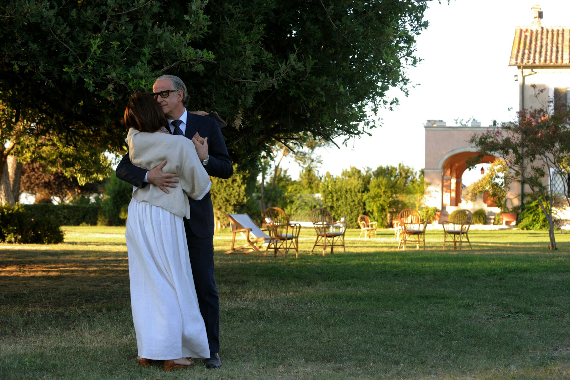 A couple dance on a green lawn.